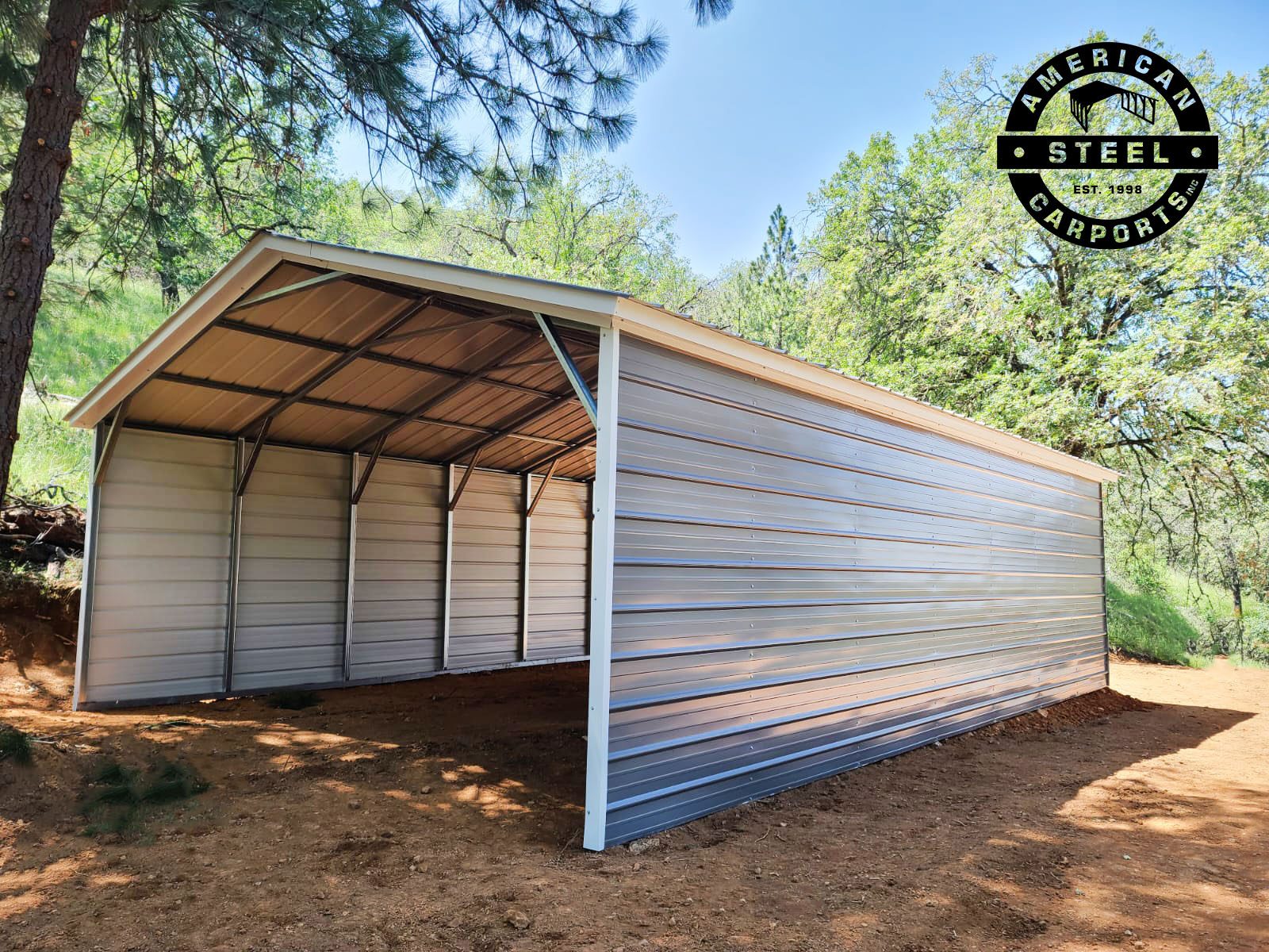 Silver steel carport with partial side panels in wooded setting