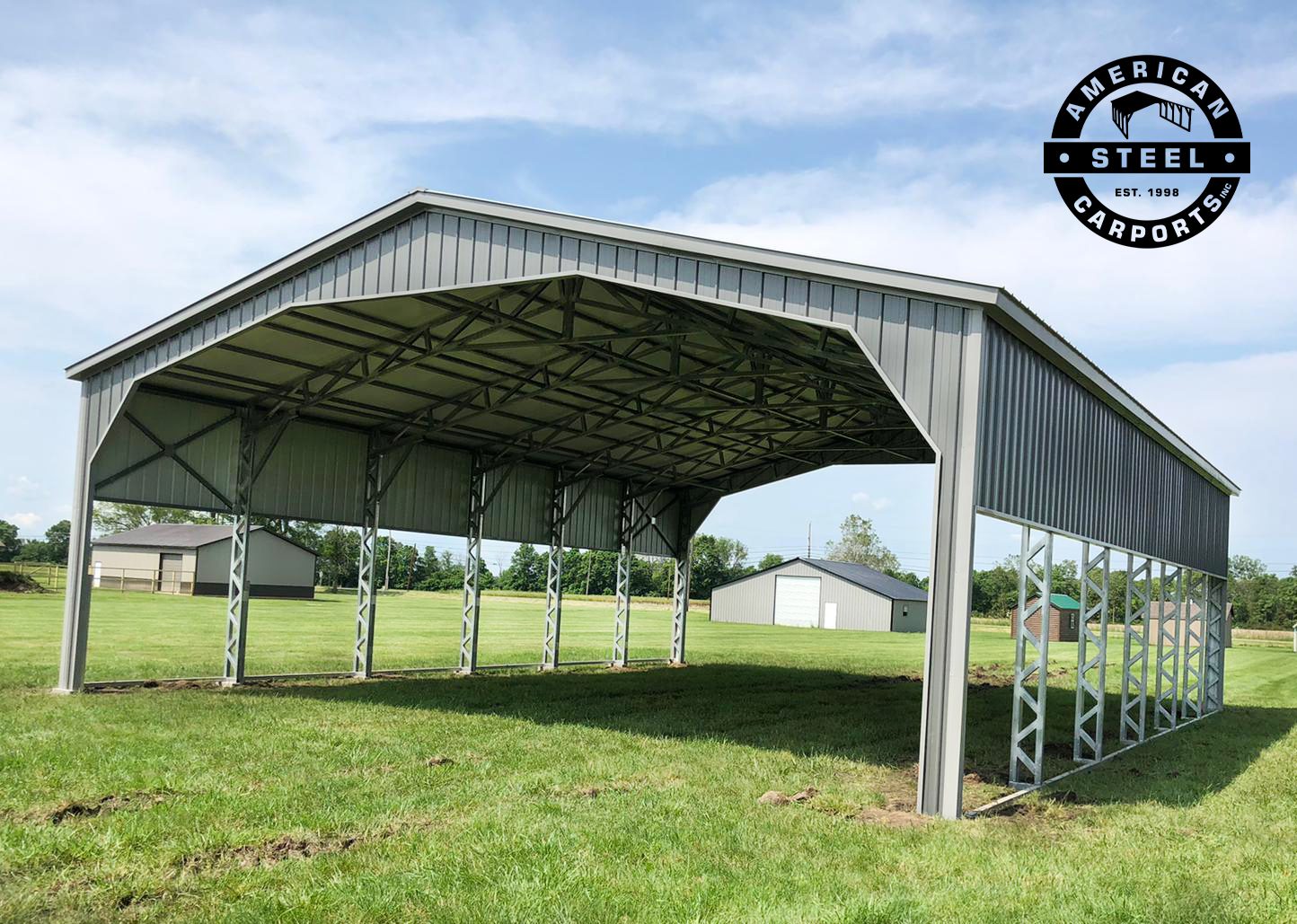 Wide-span silver steel carport pavilion on open field