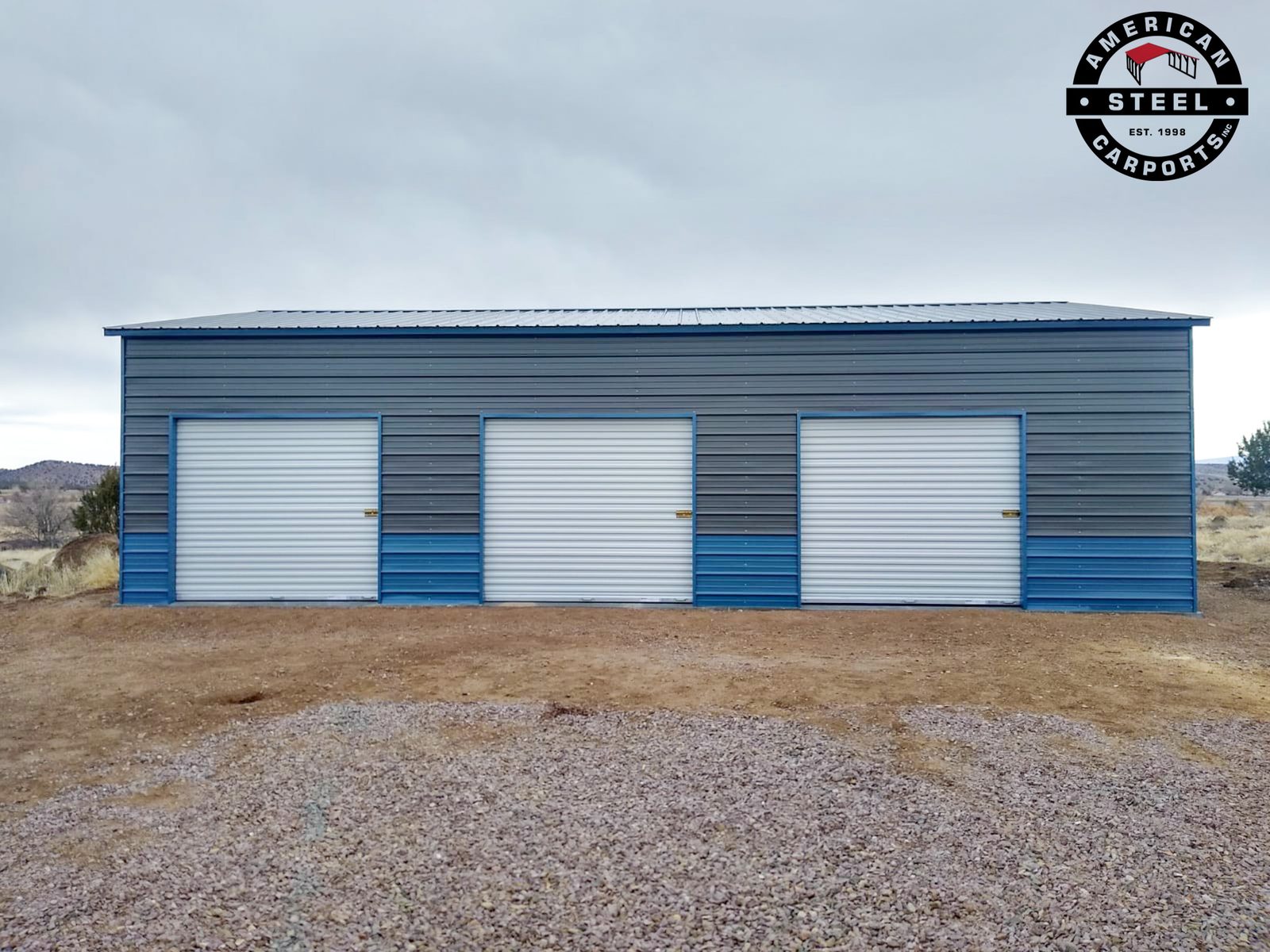Long blue and gray steel garage with three white roll-up doors
