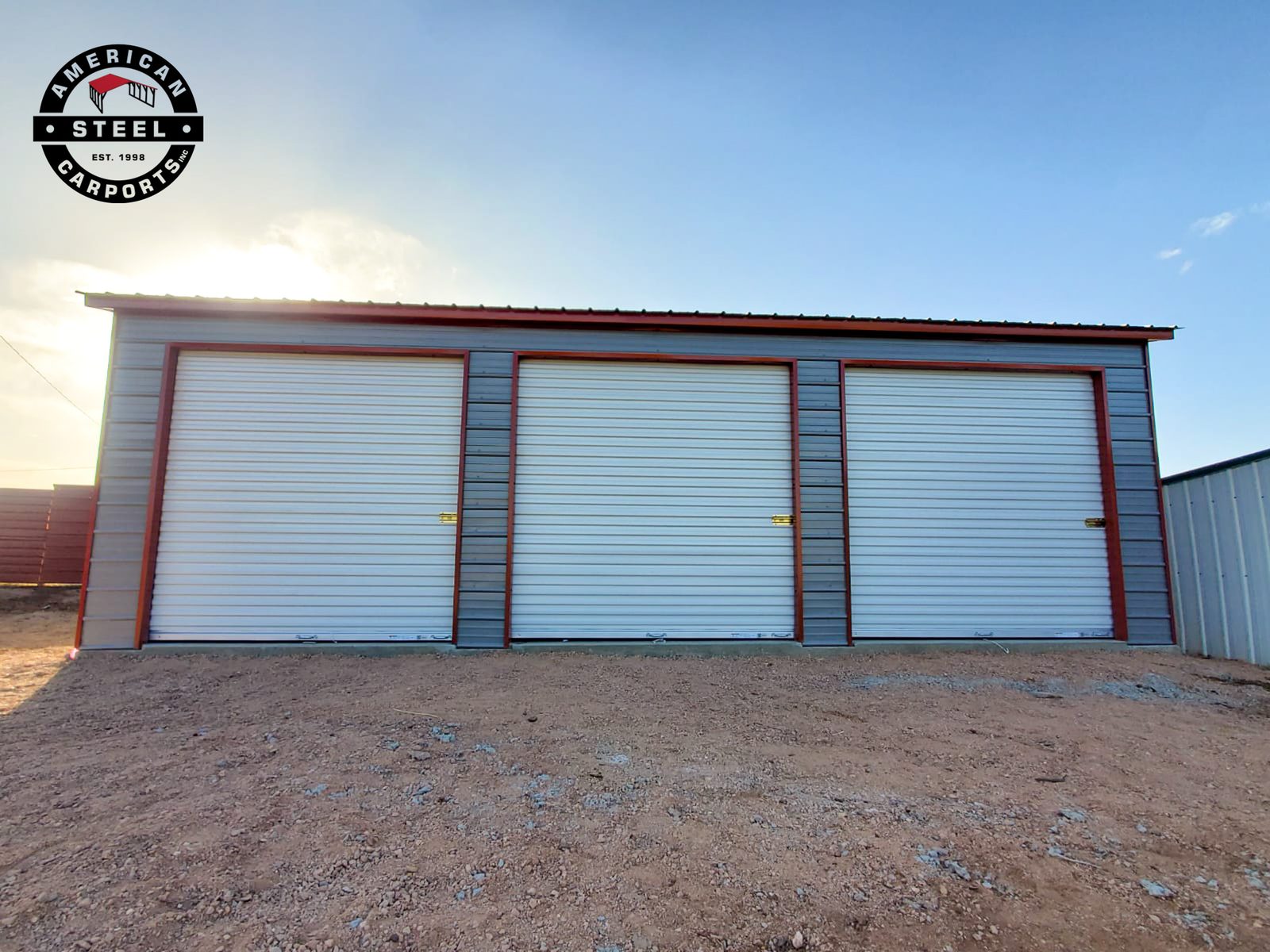 Steel garage with three white roll-up doors and red trim