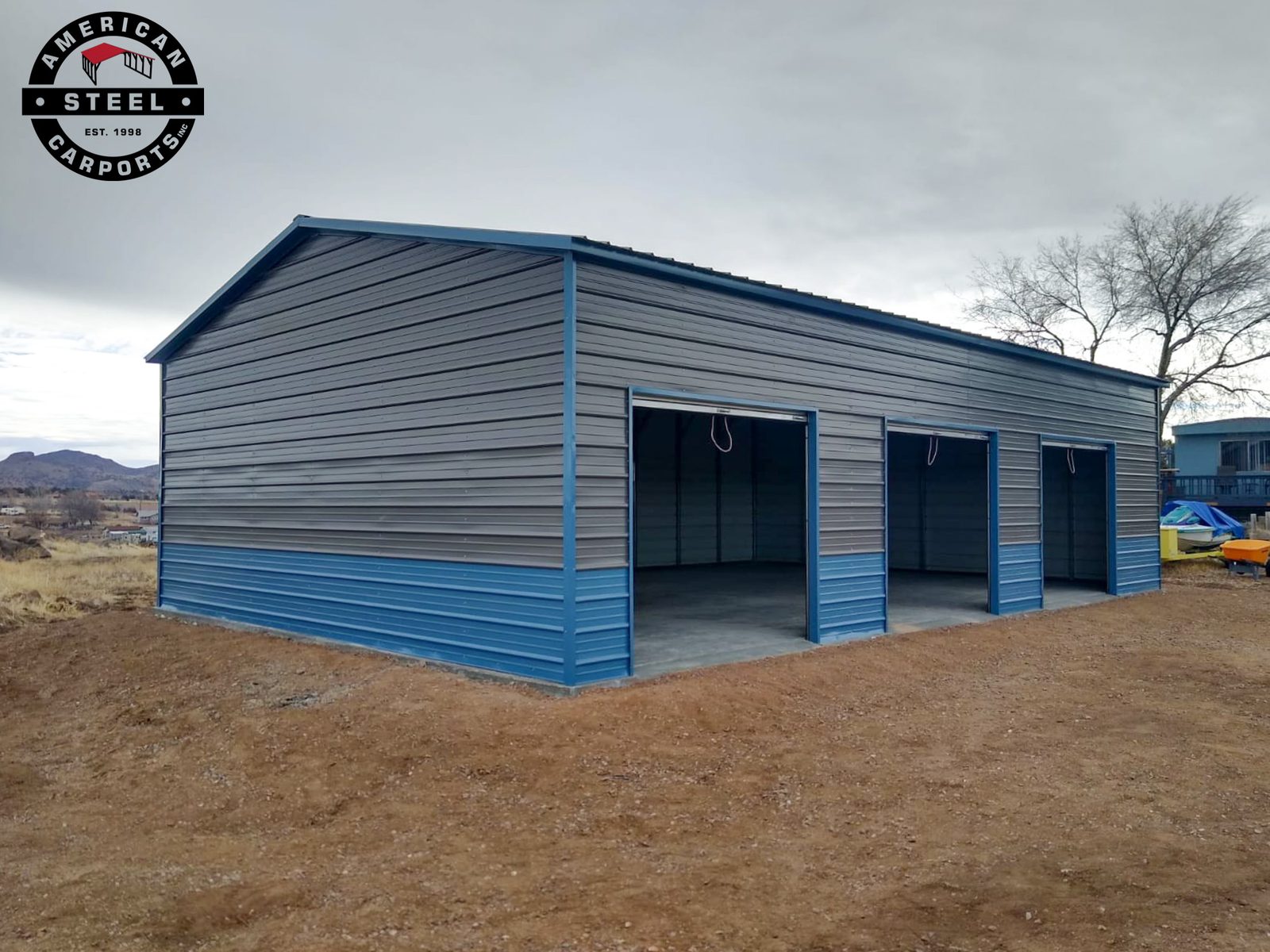 Two-tone gray and blue steel garage with double open bays in desert setting